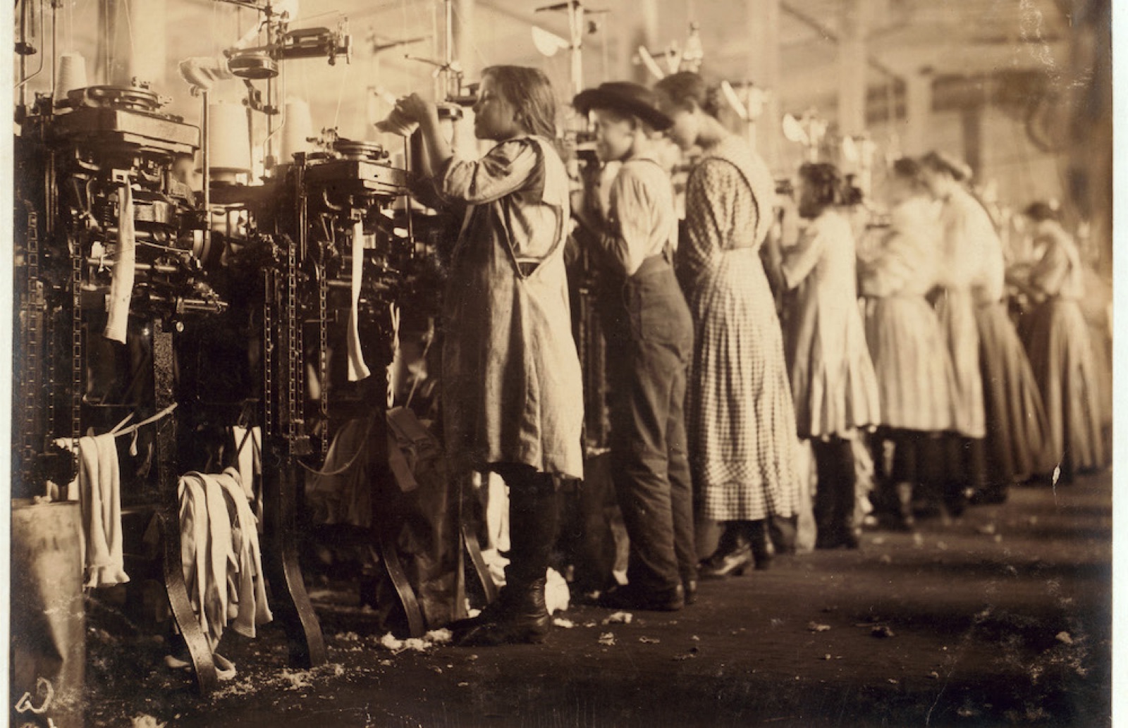 Young workers standing at spinning machines in a textile mill