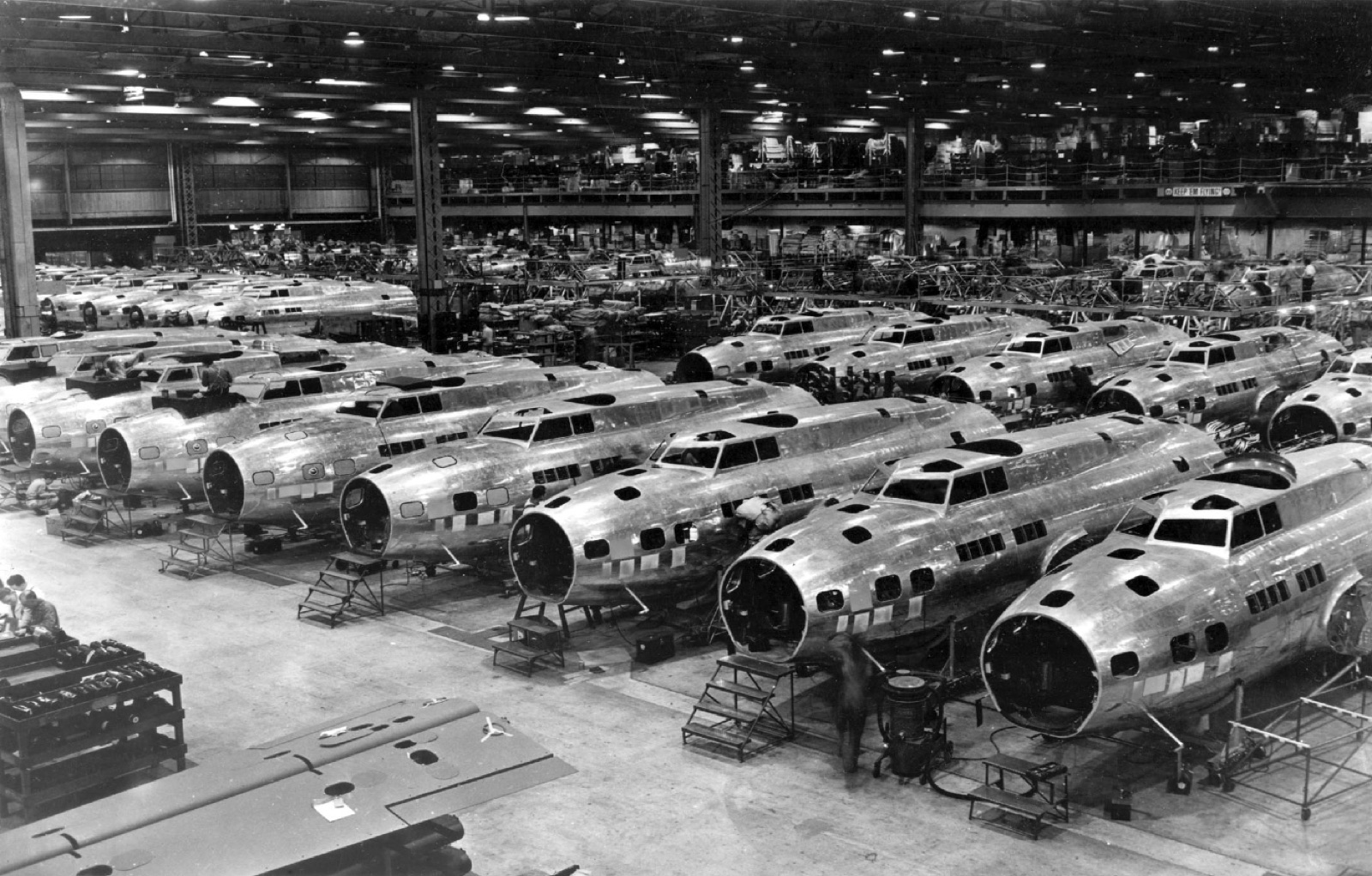 Rows of bomber fuselages under construction inside a wartime aircraft plant