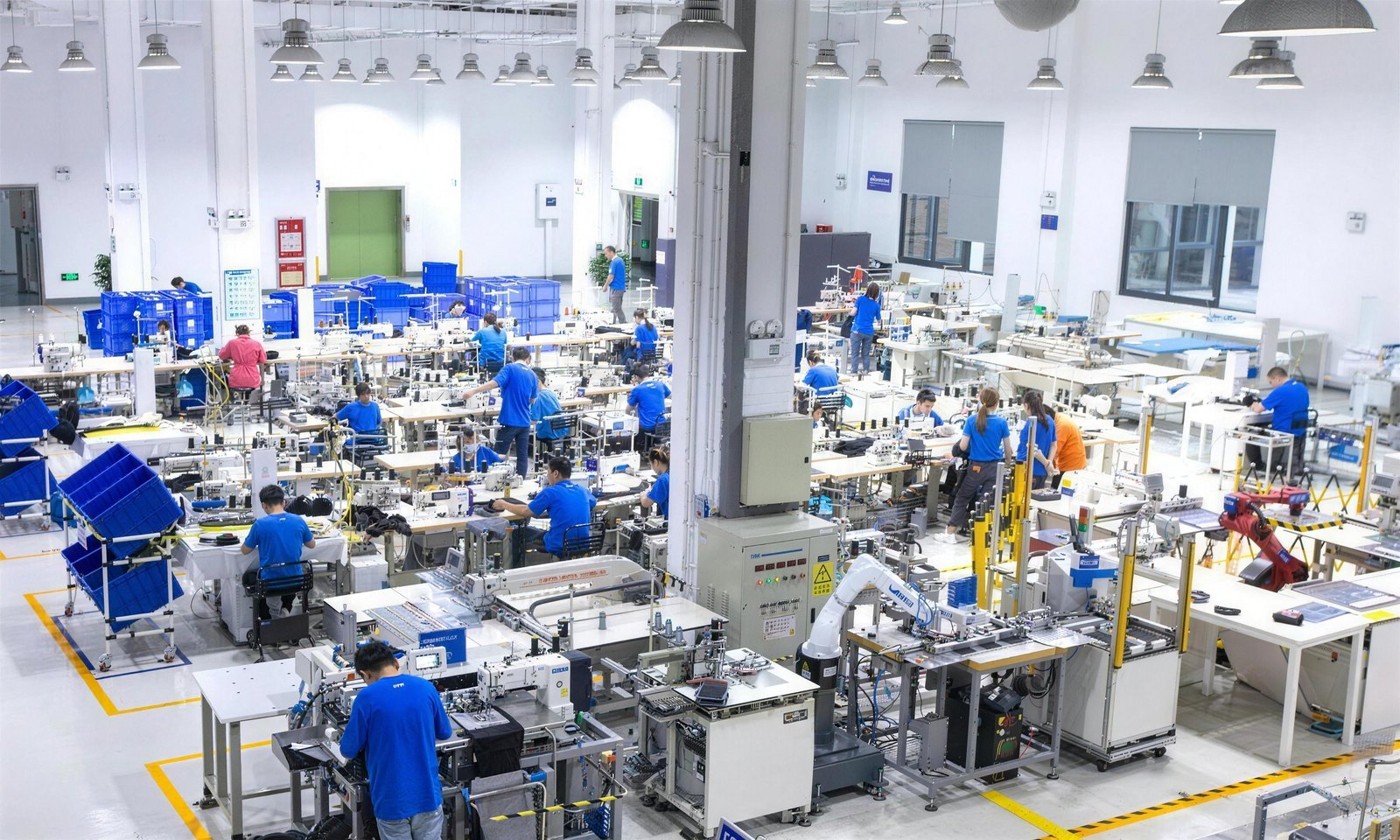 A modern Chinese factory floor with rows of workstations and robotic arms working alongside operators